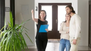 Smiling woman agent showing apartment for rent to young happy couple.