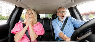 Elderly couple in a car with fearful expressions, facing the risk of an accident causing damage to others' property during their trip — cheap property damage liability insurance.